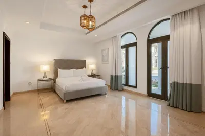 a white bedroom with a bed and large windows at Maison Privee - Villa on Beach with Private Pool The Palm Jumeirah in Dubai