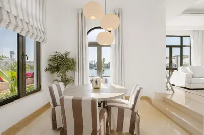 a white dining room with a table and chairs at Maison Privee - Villa on Beach with Private Pool The Palm Jumeirah in Dubai