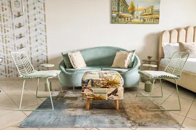 a living room with a blue couch and two chairs at Sunny Studio with Pool, Gym & Sauna in Dubai Escape in Dubai