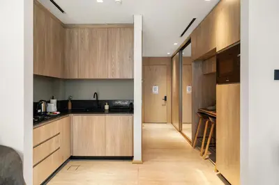 a kitchen with wooden cabinets and a hallway at Chic and Peaceful Studio with Balcony & Pool in JVC in Dubai