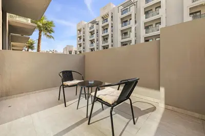 two chairs and a table on a balcony with buildings at Chic and Peaceful Studio with Balcony & Pool in JVC in Dubai