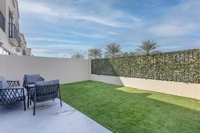 a patio with two chairs and a green lawn at Jasmine Lane, JGE - 3 Bedroom with maids' room Townhouse - Allsopp & Allsopp in Dubai