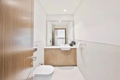 a bathroom with a toilet and a sink and a mirror at Daniels 3BR Villa plus M at La Mer With Beach Access in Dubai
