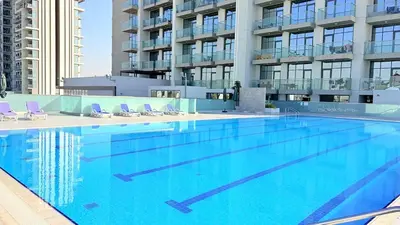 a large swimming pool with chairs and a building at Ready-to-Move 1-Bedroom in Al Furjan-103 in Dubai