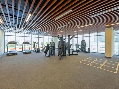 a gym with cardio equipment in a large room with windows at Spacious 2-Bedroom Apartment in Al Furjan-1010 in Dubai