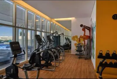 a gym with a row of treadmills and exercise bikes at Vogue JVT Novotel Near Springs Souk Mall, One Bedroom Apartment with Large Balcony and Vibrant Community view, Access to all Amenities in Dubai