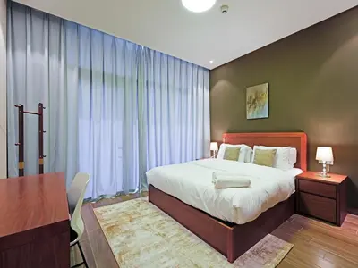 a bedroom with a large bed and a table and a desk at Well-Maintained 2-Bedroom Apartment Al Furjan-207 in Dubai