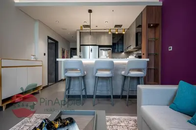 a living room with a kitchen with purple walls and stools at High Floor With Full Lake View in Dubai