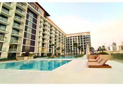 a hotel swimming pool with chairs and a building at Chic Modern Studio Unit in JVC with 65 inch TV in Dubai