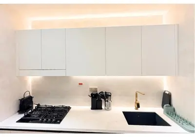 a kitchen with white cabinets and a stove top oven at Chic Modern Studio Unit in JVC with 65 inch TV in Dubai