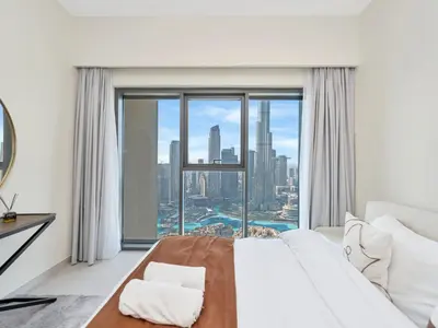 a bedroom with a white bed and a large window at Burj Royale Collection by The Luxe Manor - Downtown Dubai in Dubai