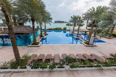 a large swimming pool with palm trees and chairs at Vacationer l 1 Bed on The Palm l City Views l Near Atlantis in Dubai