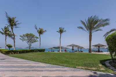 a walkway with palm trees and the ocean in the background at Vacationer l 1 Bed on The Palm l City Views l Near Atlantis in Dubai
