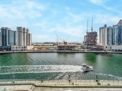 a boat in a body of water in a city at Cozy Studio with Balcony and Jacuzzi I Near Dubai Mall & Downtown I Sleeps 4 in Dubai