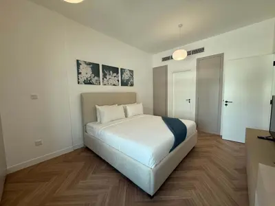 a white bedroom with a large white bed in it at High End Upgraded 1BR Living in The Greens in Dubai