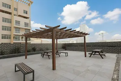 a patio with benches and a wooden umbrella at The Eden Suite Modern Luxury Meets Cozy Comfort in Dubai
