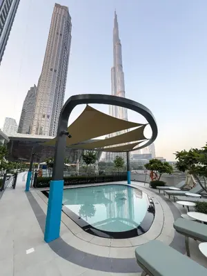 a swimming pool with a umbrella and some buildings at EMAAR GRANDE - Cozy 1 Bedroom Apartment - Infinity Pool - 1min to Dubai Mall and Burj Khalifa in Dubai