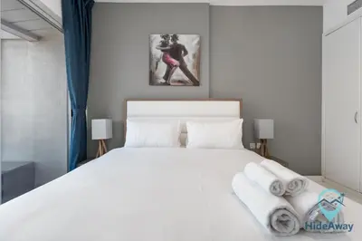 a bedroom with a large white bed with towels on it at Elegant 1BR l Steps to Metro l Free Parking in Dubai