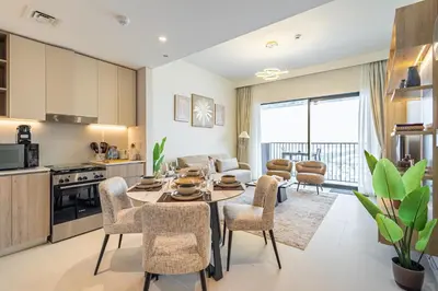 a kitchen and living room with a table and chairs at Superhost - 1BR Apartment , Pool & Gym , Near Dubai Hills Mall in Dubai