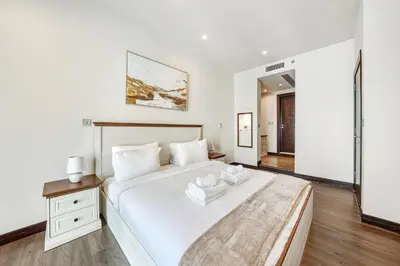 a bedroom with a large white bed with a wooden floor at Modern Smart & Spacious 1BR Business Bay near Downtown Dubai in Dubai