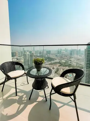 three chairs and a glass table on a balcony at Soft-Toned 1BR in Binghatti Gardenia with Pool & Gym in Dubai