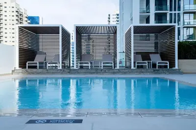 a swimming pool with chairs in front of a building at Soft-Toned 1BR in Binghatti Gardenia with Pool & Gym in Dubai
