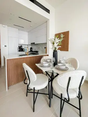a dining room with a table and chairs and a kitchen at Soft-Toned 1BR in Binghatti Gardenia with Pool & Gym in Dubai