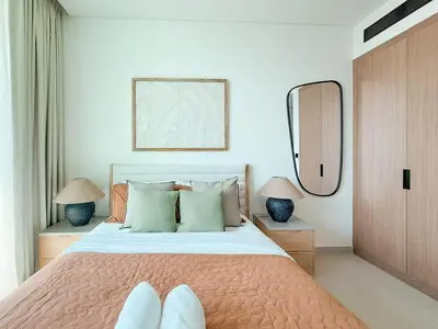 a bedroom with a bed with two lamps and a mirror at Binghatti Azure Minimal Luxe Studio with Pool & Gym in Dubai