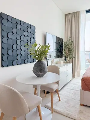 a living room with a table and a vase with a plant at Binghatti Azure Minimal Luxe Studio with Pool & Gym in Dubai