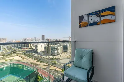 a blue chair on a balcony with a view of a city at Modern Studio Near Miracle Garden & Dubai Hills in Dubai