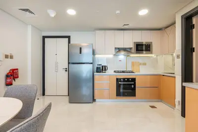 a kitchen with a stainless steel refrigerator and a table at Brand New Home with Amazing Facilities in Dubai