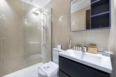 a bathroom with a toilet and a sink and a shower at Stylish 1BR Apartment Near Silicon Mall & Airport in Dubai