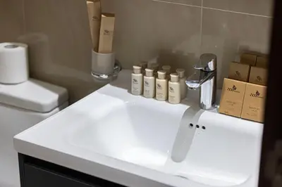 a white sink in a bathroom with a toilet at Stylish 1BR Apartment Near Silicon Mall & Airport in Dubai