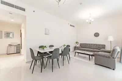 a living room with a couch and a table and chairs at HAVN - 1 bed in May Residence, JVC in Dubai