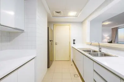a white kitchen with a sink and a door at JBR Al Bateen Residences By Luxe Living Collection - Private Beach and Sea Views in Dubai
