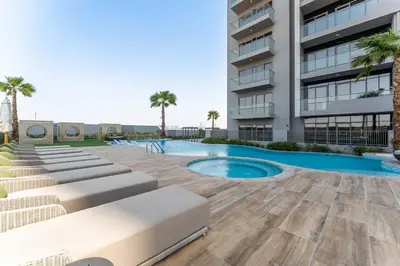 a building with a swimming pool next to a building at Brand New 1BDR with Pool, Jacuzzi, Sauna, Gym in Dubai