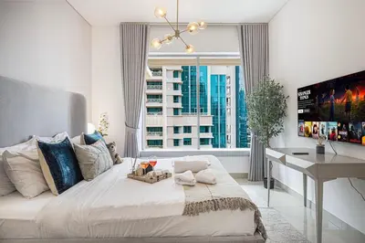 a bedroom with a large bed with a desk and a window at Stunning Burj & Fountain View Downtown 29 Blvd in Dubai
