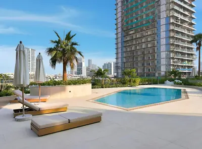a swimming pool with chairs and umbrellas and a building at New Chic 1BR Apt with Private Pool & City View in JVC in Dubai