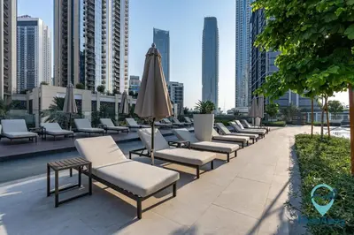 a row of chaise lounge chairs and an umbrella at Stunning 1BR l Creek Crescent Suite in Dubai