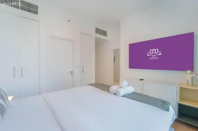 a white bedroom with a large tv on the wall at 29 Boulevard-Burj Khalifa View-Downtown Dubai-Lit Apartment in Dubai