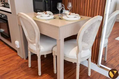 a wooden table with two chairs and a table with wine glasses at Vogue JVC Binghatti Phoenix near Circle Mall, Studio Apartment with Balcony and Access to all Amenities in Dubai