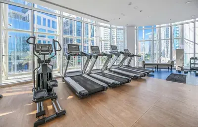 a gym with rows of tread machines in a room with windows at Luxury 1BR near Burj Khalifa Business Bay Free Parking in Dubai