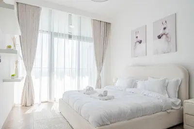 a white bedroom with a large white bed in front of a window at Stunning Burj Khalifa View Luxury 2BR Business Bay in Dubai