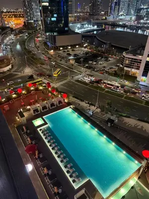 a large swimming pool in a city at night at Mag318 downtown Luxury-5 Minutes walk to Burj&mall in Dubai