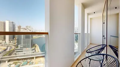 a balcony with two chairs and a view of a city at Stunning 2BR Canal & Burj Khalifa Partial View 4 in Dubai