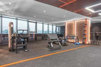 a gym with exercise equipment in a building with windows at Brand-New Elegant Stay Premium Amenities JVT in Dubai