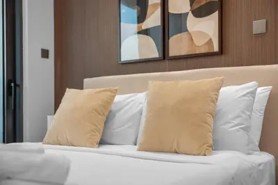 a bed with white pillows and paintings on the wall at Brand-New Elegant Stay Premium Amenities JVT in Dubai