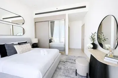a white bedroom with a large bed and a mirror at Premium 1BR W Private Pool Binghatti Royale in Dubai