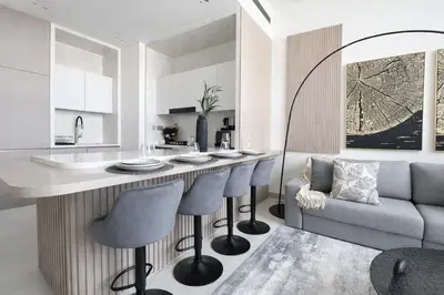 a kitchen with a bar with chairs and a couch at Premium 1BR W Private Pool Binghatti Royale in Dubai