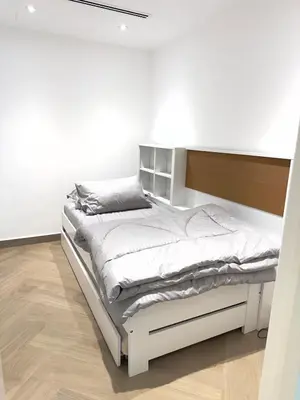 a white bed in a room with a white wall at Elegant apartment in a prime location in Dubai
